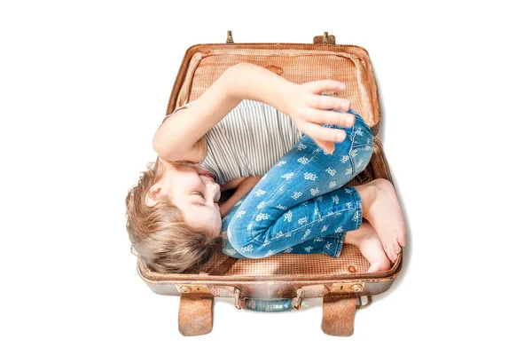 Sonriente chica se encuentra en una vieja maleta marrón sobre un fondo blanco — Foto de Stock