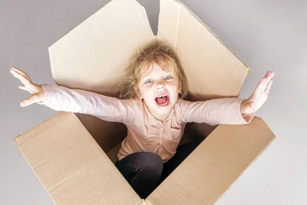 A menina grita dentro de uma caixa de papelão. Tonificado . — Fotografia de Stock