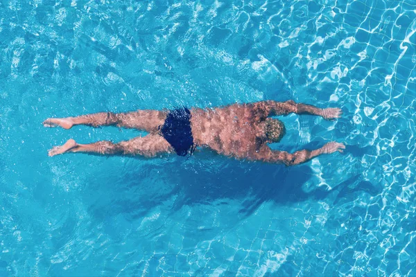 Ο άνθρωπος κάτω από το νερό σε μια διαφανή πισίνα. Θέα από πάνω. — Φωτογραφία Αρχείου