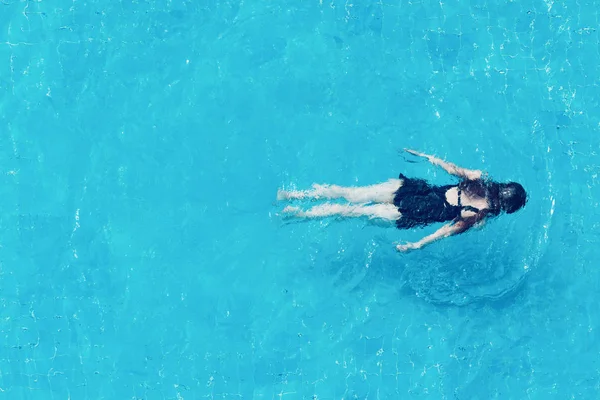 Top vy över en flicka som simmar under vattnet i en pool. — Stockfoto