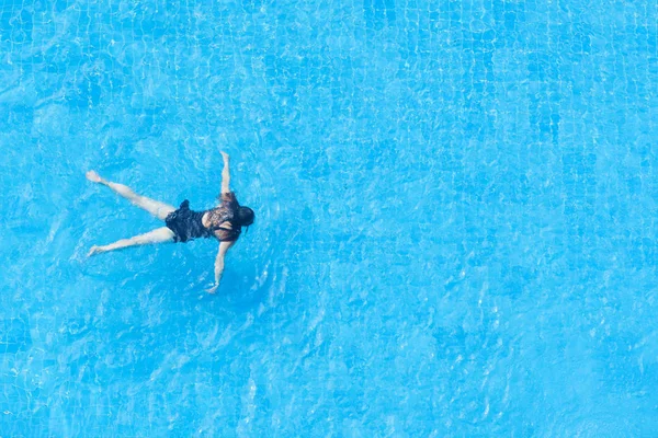 Vue du dessus d'une fille en maillot de bain noir dans la piscine . — Photo