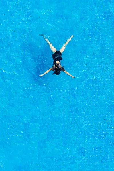 Das Mädchen im schwarzen Badeanzug schwimmt im Pool, Draufsicht. — Stockfoto