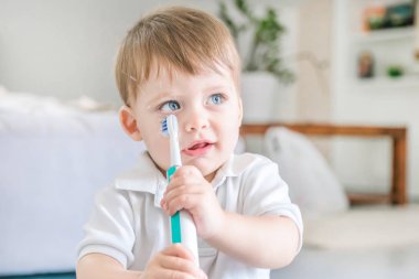 Güzel mavi gözlü sarışın bebek bir diş fırçası tutar.