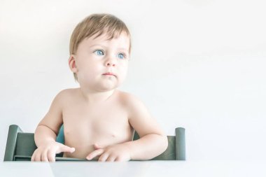 Sevimli sarışın mavi gözlü bebek masada oturan.