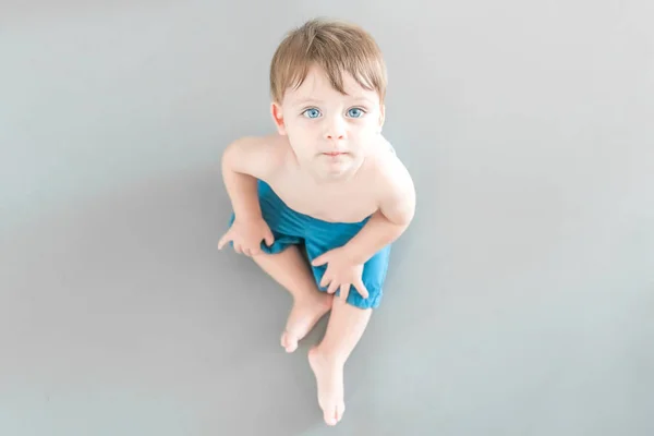 Beautiful blue-eyed baby sitting on the floor, top view. — Stock Photo, Image