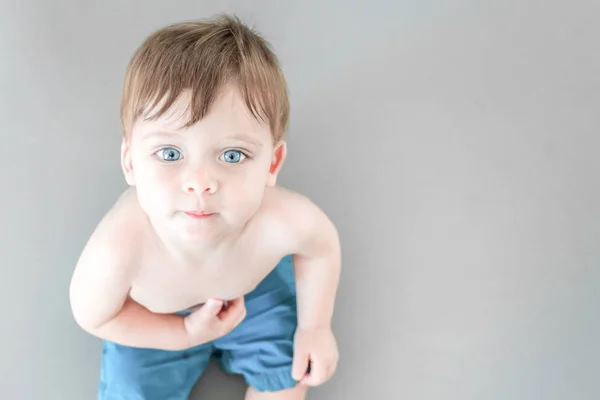 Cute blue-eyed baby sitting on the floor, top view. — Stock Photo, Image