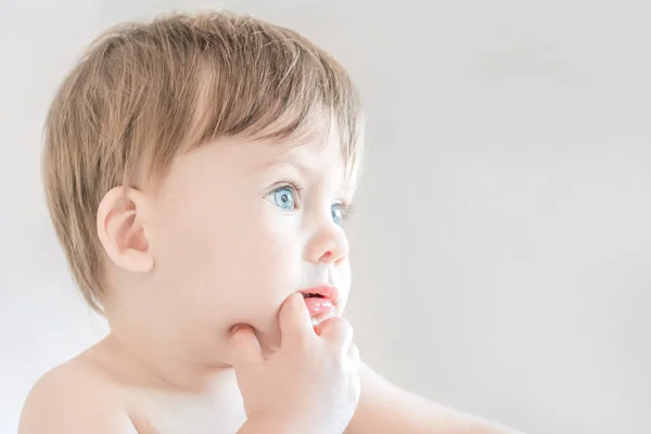 Rubia de ojos azules bebé con un dedo en la boca de cerca . —  Fotos de Stock