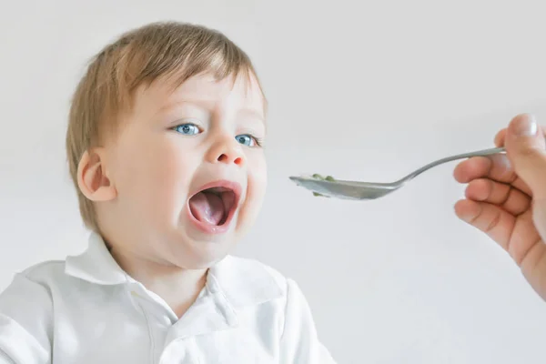 Mamá alimenta a su bebé con una cuchara. Primer plano . — Foto de Stock