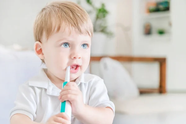 Pequeño niño rubio de ojos azules cepillándose los dientes con un cepillo de dientes i —  Fotos de Stock