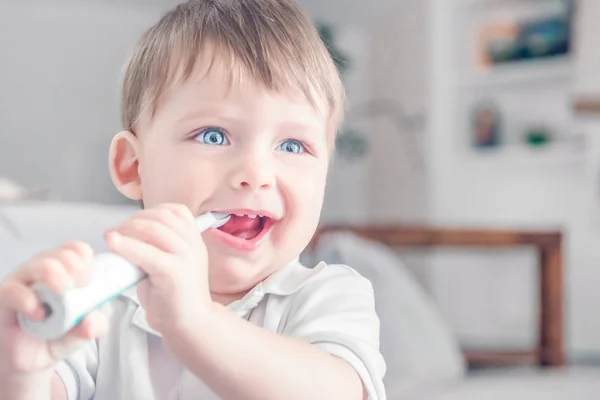 Sonriente niño pequeño cepillándose los dientes en la habitación . — Foto de Stock