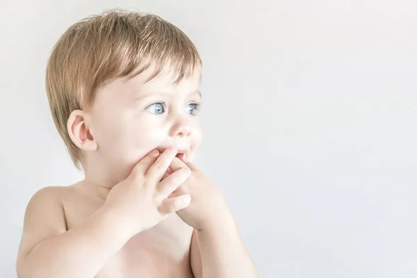 A cute blue-eyed blond babe with a finger in the mouth. — Stock Photo, Image