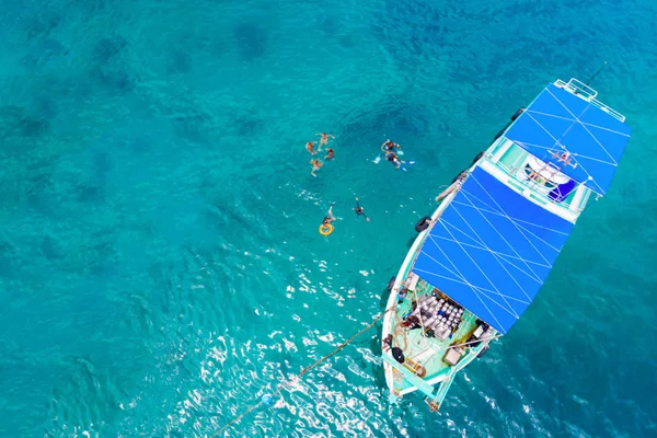 Top view of people floating near the yacht on the high seas.