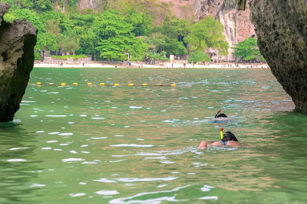 Los buceadores nadan cerca de una isla rocosa, cerca de la playa . — Foto de Stock