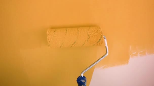 Schildert een oranje muur met een roller — Stockvideo