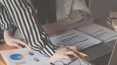 İş kadını elinde kalem ve grafik kağıtlarıyla gelecek yıl belirlenen hedeflere ulaşmak için satışları planlamak üzere toplanıyor