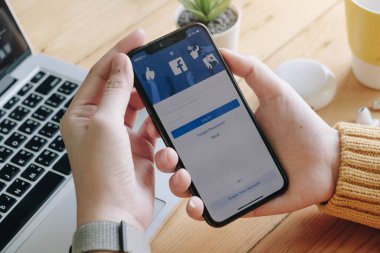 CHIANG MAI, THAILAND - 7 Haziran 2020: Facebook sosyal medya uygulaması logosu giriş, mobil uygulama ekranı için kayıt sayfası iPhone X 'de (10) kişinin elinde e-ticaret alışveriş otobüsleri üzerinde çalışıyor