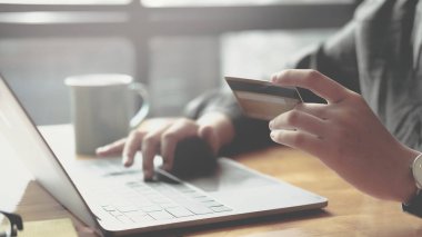 Çevrimiçi ödeme, kredi kartı tutan bir kadının elleri ve online alışveriş için dizüstü bilgisayar.