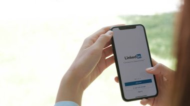 CHIANG MAI, THAILAND - JUL 12 ,2020: Woman holding iphone X mobile phone with Linkedin application on the screen. Linkedin is a business and employment oriented social networking service.	