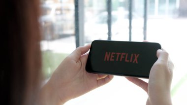 CHIANG MAI, THAILAND, MAR 25, 2020: Apple iPhone X üzerinde Netflix logosu olan akıllı telefonu tutan kadın. Netflix, dünya çapında bir dizi ve film sağlayıcısıdır..