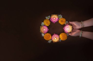 İki el Diwali mumlarını tutuyor, kadife çiçekleriyle çevrili, festival boyunca beraberliğin ruhunu somutlaştırıyor..