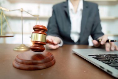 Davalı bir avukat, elinde bir dizüstü bilgisayarla masada otururken hukuki mesleği ve otoriteyi temsil eden bir tokmak tutuyor..