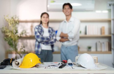 Çağdaş bir ofiste poz veren iki mühendis, inşaat planlamasında takım çalışması ve profesyonelliği sergiliyor.