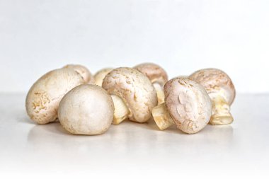 Mutfak masasının hafif yüzeyinde yemek pişirmek için küçük beyaz mantar yığını.