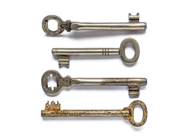 Несколько старых, изношенных ключей от потерянных замков, изолированных на белом фоне
