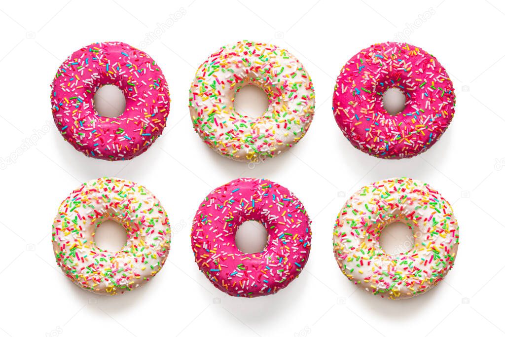 Several traditional American doughnuts with pink and vanilla icing and multicolored sprinkles, isolated on a white background