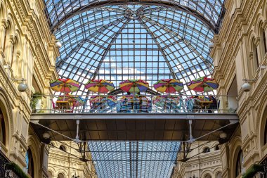 Moskova, Rusya, 07.10.2020. Metal köprüde şemsiyeli kafe, tarihi GUM mağazasında cam ve metalden yapılmış açılış kubbesinin altında, kırmızı kare üzerinde.