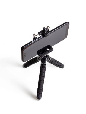 Bacakları üzerinde siyah bir telefon olan siyah bir tripod, beyaz bir arka planda izole edilmiş.