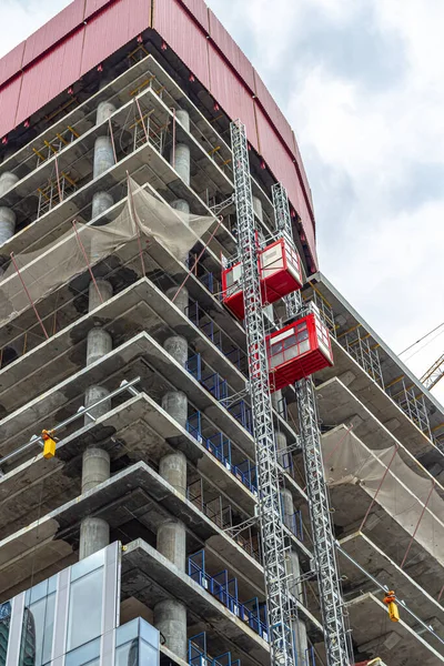 二つのエレベーターは 建設中の新しい高層ビルの建設現場で働くために労働者を持ち上げる — ストック写真