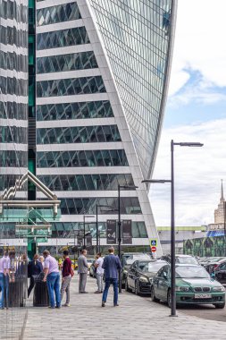 Moskova, Rusya, 08.07.2020. Bölgedeki insanlar, Evrim gökdeleninin arka planına karşı Moskova 'nın iş bölgesinde cam ve betondan yapılmış modern, fütürist bir bina.