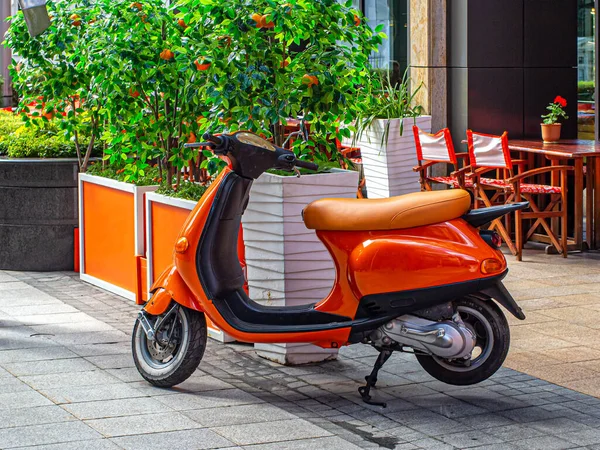 オレンジスクーター オレンジテーブルと椅子のあるカフェの近くに駐車 オレンジボックスのオレンジと人工木 — ストック写真