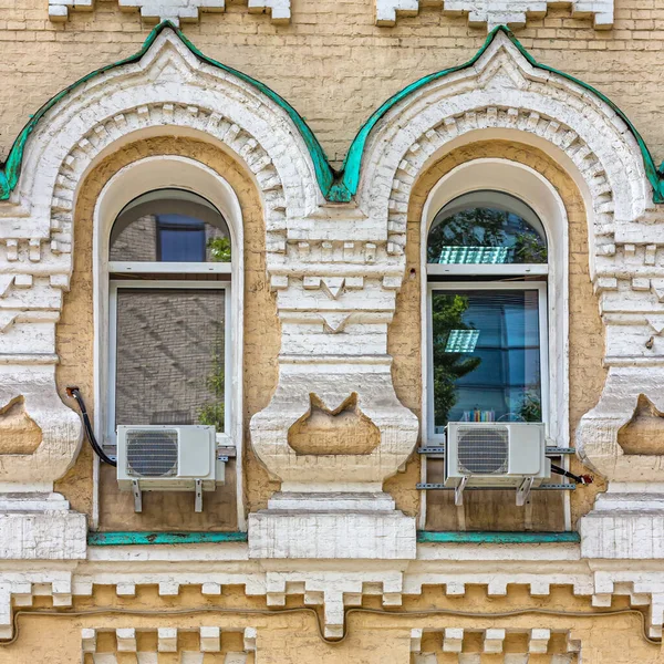 Moscow, Russia, 08.21.2020. Wall of the house built in the 19th century, for widows and orphans, Windows and architraves are decorated in pseudo-Russian style. Plastic Windows and air conditioners