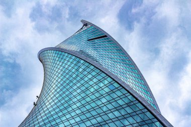 Moskova, Rusya, 08.07.2020. Moskova 'daki spiral gökdelen evriminin alt görüntüsü. Bükülmüş cam duvarda, sanayi tırmanışçılarının figürleri cam camları yıkarken zar zor görülebiliyor.