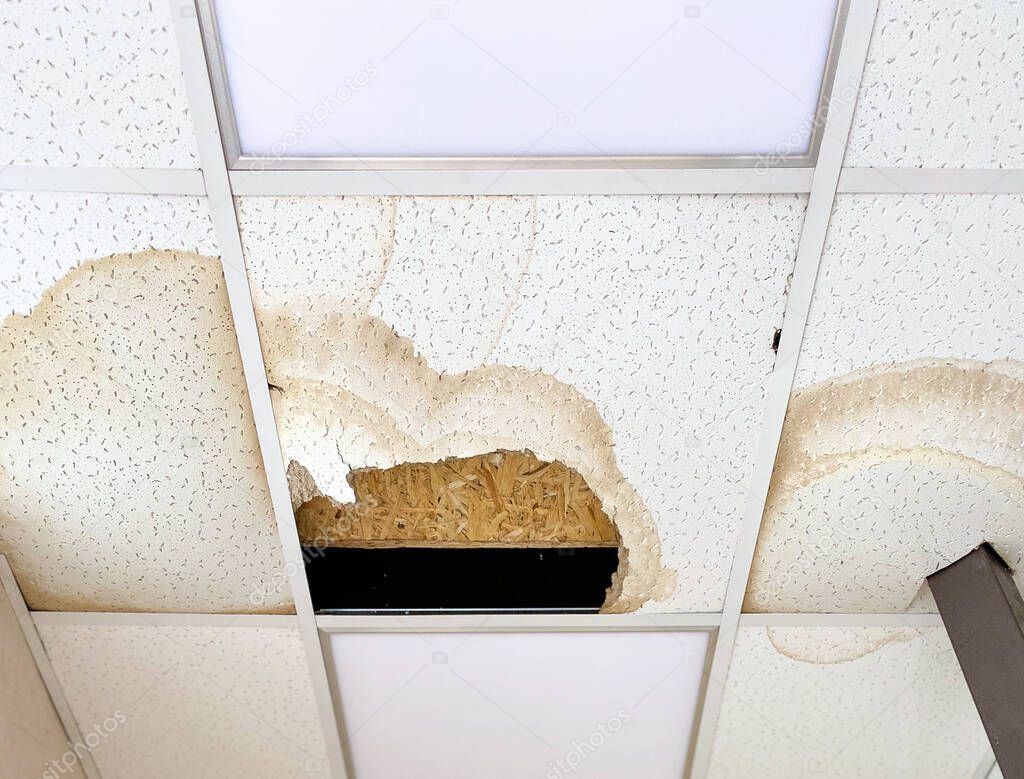 A large hole in the ceiling and stains from the water, due to damage to the roof during rain.