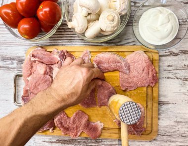 Evde Fransızca et pişirme süreci. Erkek ellerinin domuz etini dövmesi. Ev yapımı gıda kavramı, uygun beslenme.