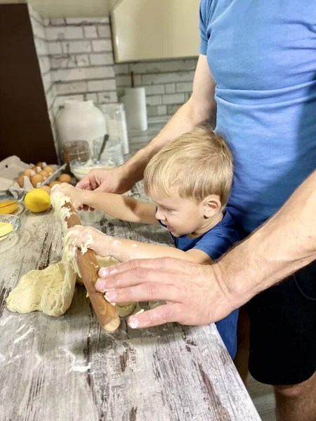 Light skinned child and man kneading dough to make buns / pastry. Parent-child connection concept, home cooking. Free space.