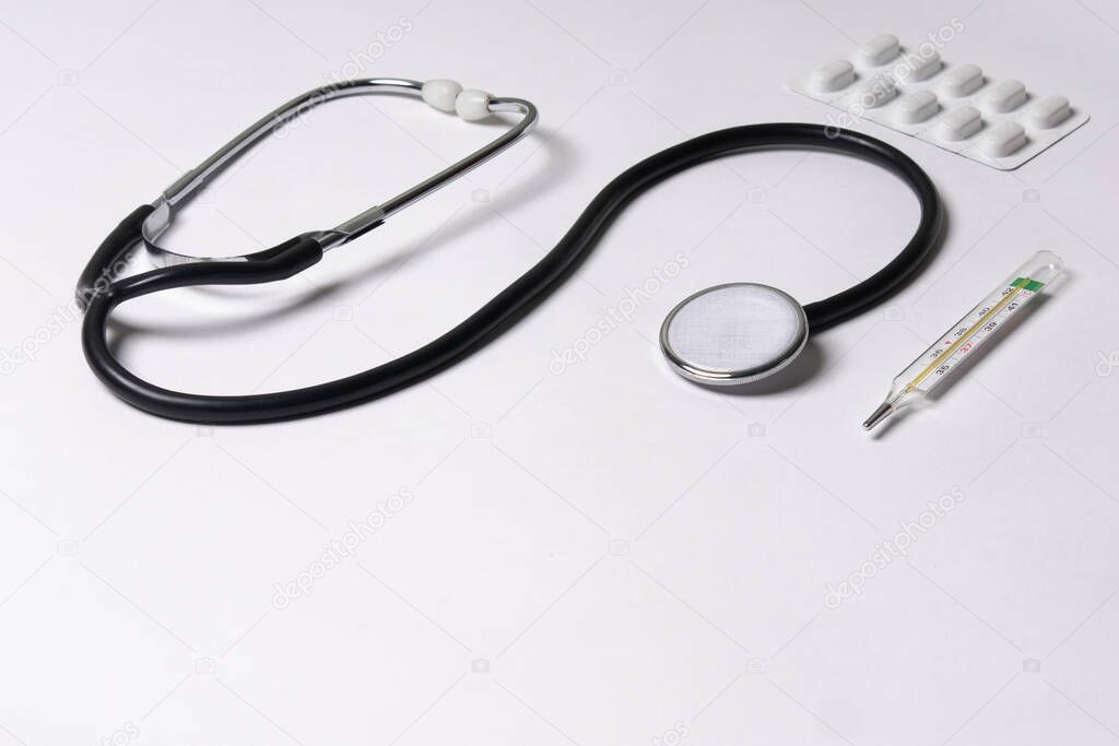 Stethoscope, thermometer, pills, on a white background, healthcare coronavirus, cancer, painand treatment, pharmaceutical medicine concept