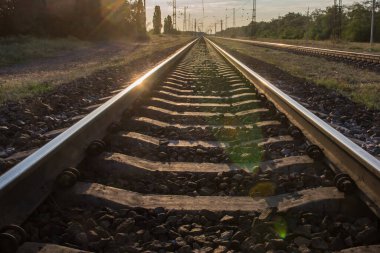 Raylar gün batımının arka planına doğru uzanıyor.