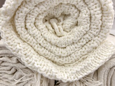 Pastel bej renginde yün kumaş örülmüş. Yuvarlak bir ekoseye sarılmış. Yakından.