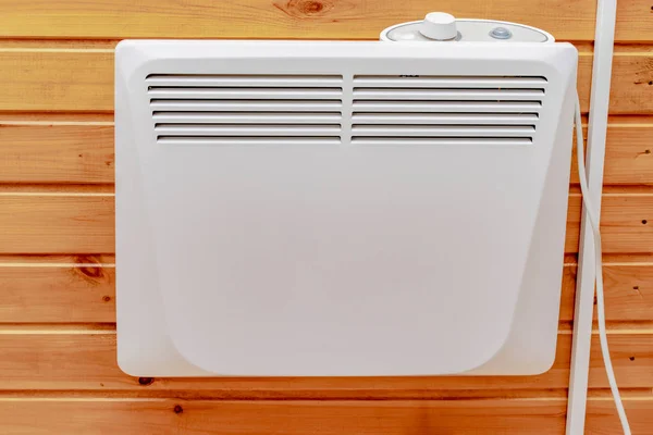 Принудительный водонагреватель на деревянной стене загородного дома, электрический радиатор для отопления дома и контроля комфорта в комнате — стоковое фото
