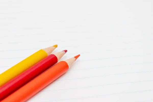 Crayons colorés sur le fond d'une feuille blanche doublée de bloc-notes close-up avec espace de copie — Photo