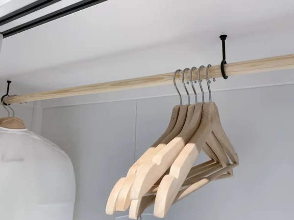 Group of wooden empty handgers in a wardrobe, hanging on a wooden tube — Stock Photo, Image