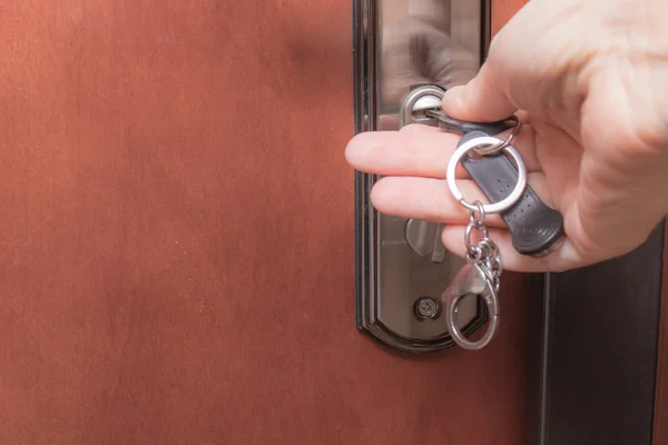 Woman hands locking up or unlocking front entrance doorwith a key