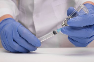 Mavi eldivenli doktor şırıngayı aşı, aşı ve grip ve koronavirüse karşı aşılama ile dolduruyor.