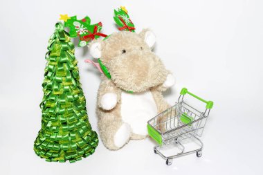 Teddy Hippo, Noel ağacı süslemesi ve alışveriş arabası olan yumuşak oyuncak, beyaz arka planda tramvay.