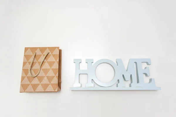 Un segno di casa e un sacchetto di carta artigianale shopping su sfondo bianco, l'acquisto di concetto di casa — Foto Stock