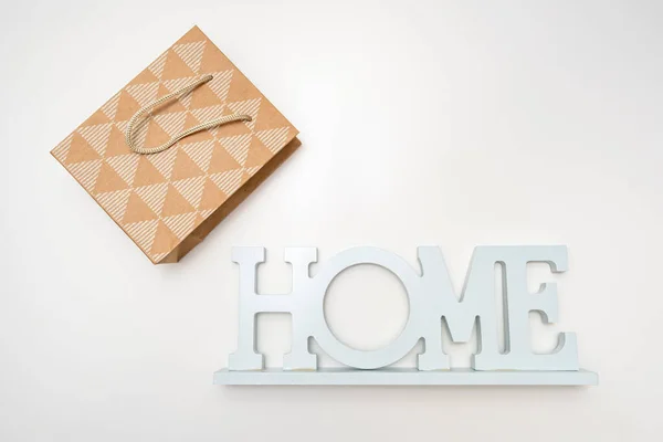 Un segno di casa e un sacchetto di carta artigianale shopping su sfondo bianco, l'acquisto di concetto di casa — Foto Stock